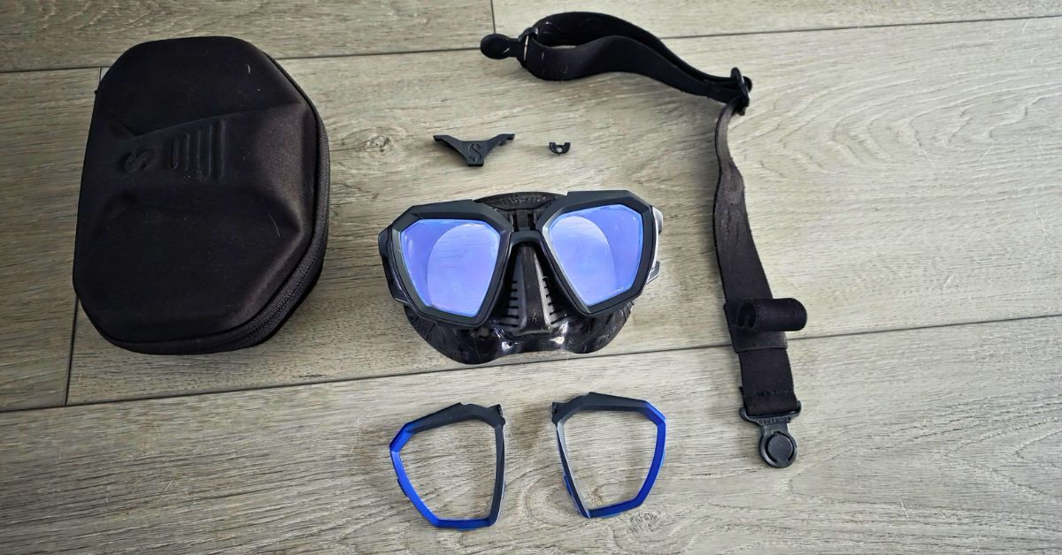 SCUBAPRO D-Mask showing wear from years of use. Surrounded by all the included accessories. For article titled SCUBAPRO D-Mask Review